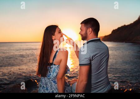 Summer joyful vacation. Man playfully touching a woman's nose. Rear view. Stock Photo