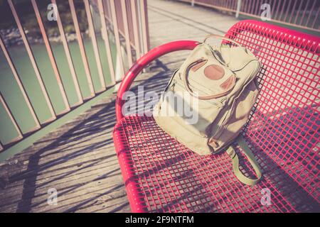 Vintage backpack is lying on red bench Stock Photo