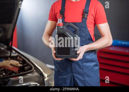 Auto mechanics hands holding canister in workshop Stock Photo