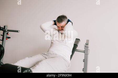 a novice athlete with a tense face performs exercises on the press. lying on the bench. body care Stock Photo