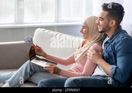 Side view of muslim couple using laptop at home Stock Photo