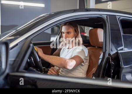 Serious man in car salon wiping steering wheel Stock Photo