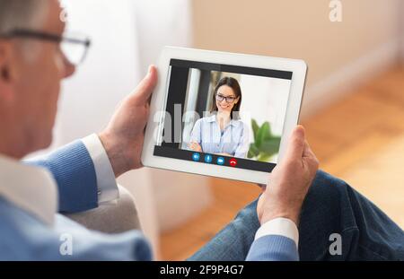 Senior Man Using Digital Tablet At Home For Video Chat With Daughter Stock Photo