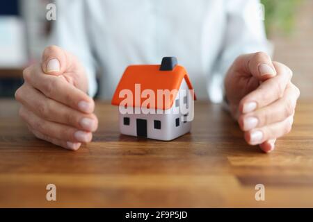 Female hands hugging small toy house closeup Stock Photo