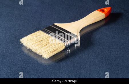 Paint brush with wooden handle on the table. Tools on a blue background with reflection Stock Photo