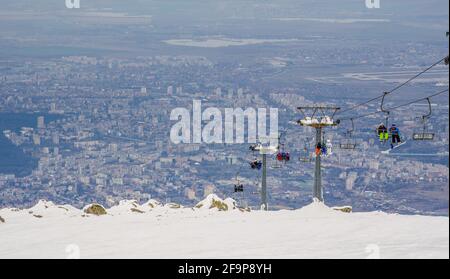 skilift is bringing skiers to the top of vitosha mountain in bulgaria. capital of the country sofia is on background. Stock Photo