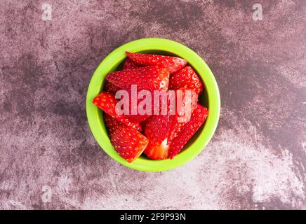 Top view of a small green bowl filled with plain Greek yogurt on a dark red mottled tabletop. Stock Photo