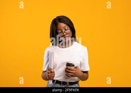 Tired black lady student with books sleeping on yellow Stock Photo
