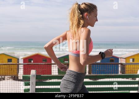 Caucasian woman exercising jogging on a promenade by the beach. healthy outdoor leisure time by the sea. Stock Photo