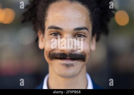 Portrait of mixed race male with moustache looking to camera and smiling. independent small business in a city. Stock Photo