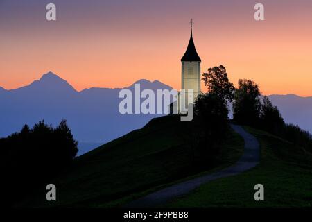 Jamnik church sunrise, landscape in Slovenia, nature in Europe.  Foggy Triglav Alps with forest, travel in Slovenia. Beautiful sunrise with blue sky, Stock Photo