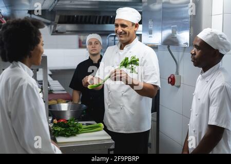 Diverce race male and female professional chefs preparing vegetables. working in a busy restaurant kitchen. Stock Photo