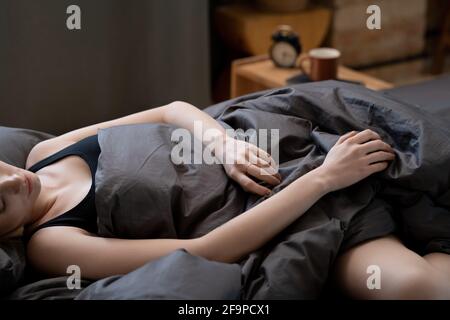 Close-up of young woman lying on the bed under the blanket at night in the bedroom Stock Photo