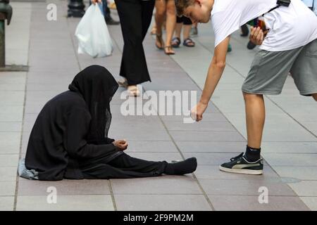 20.07.2018, Tbilisi, Tbilisi, Georgia - Boy gives money to a beggar woman. 00S180720D642CAROEX.JPG [MODEL RELEASE: NO, PROPERTY RELEASE: NO (c) caro i Stock Photo