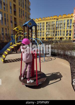 A girl of eight years in crash helmet riding on carousel. Child on merry-go-round Stock Photo