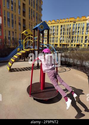 A girl of eight years in crash helmet riding on carousel. Child on merry-go-round Stock Photo