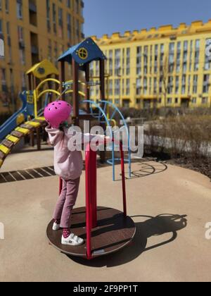 A girl of eight years in crash helmet riding on carousel. Child on merry-go-round Stock Photo