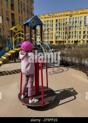 A girl of eight years in crash helmet riding on carousel. Child on merry-go-round Stock Photo