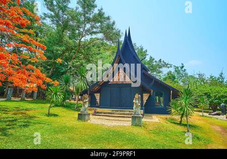 CHIANG RAI, THAILAND - MAY 11, 2019: The facade of the Xieng Thong House with gable (pyathat) roof, carved decorations and sculptures of Yaksh guards, Stock Photo