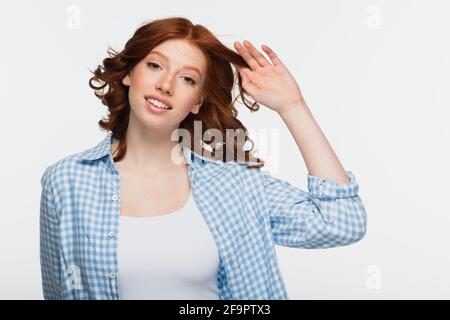 young woman in blue checkered shirt adjusting red hair isolated on white Stock Photo