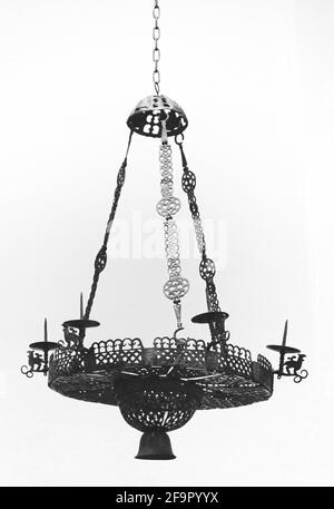 Chandelier for candles isolated on white background. Old metal forged lamp. Hanging candlestick, which was hung in locks under the ceiling Stock Photo