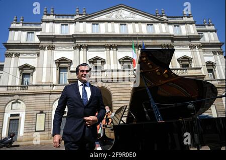 Milan, Italy. 20th Apr 2021. Conductor Alberto Veronesi performs at the piano during a flashmob in front of Teatro alla Scala theatre in Milan Italy on April 20, 2021 to raise awareness on the conditions of entertainment business workers due to the pandemic Credit: Piero Cruciatti/Alamy Live News Stock Photo