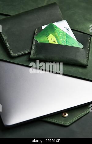 green wallet and genuine leather laptop case and cardholder lie on table. Top view Stock Photo