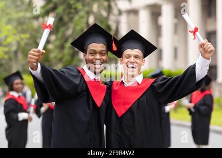 Happy guys students posing together next to university Stock Photo