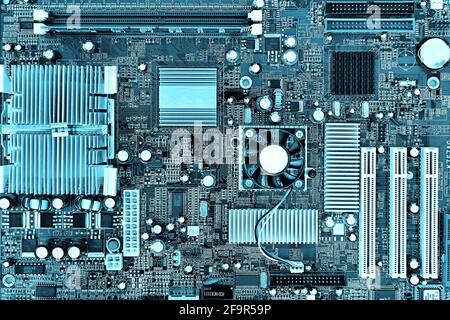 Motherboard, printed circuit board in a desktop personal computer. Teal colored, Cyberpunk design. Stock Photo