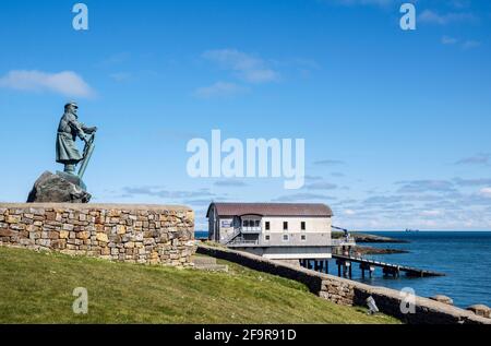 Statue of Coxswain Richard (Dic) Evans 1905-2001 with new Lifeboat Station beyond.  Moelfre, Isle of Anglesey, Wales, UK, Britain Stock Photo