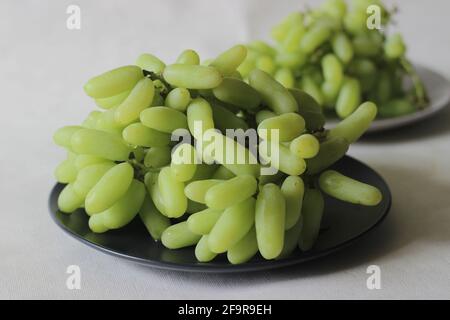 Indian variety of green seedless grapes with a long finger like shape. Shot on white background. Stock Photo