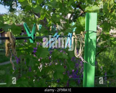 Colorful pins hanging on a wire in the yard outdoors. Rural background, simple life home concept. Stock Photo