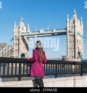 London people lifestyle city tourist woman looking at view of Tower Bridge in red trench coat. Bridge. Stylish elegant lady fashion girl walking Stock Photo