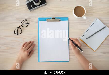 Female hands writing plan for trip in empty notepad at the wooden desk, top view, copy space for text. Stock Photo