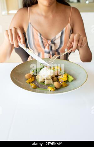 Young woman holding eating utensils over fine dining plate Stock Photo