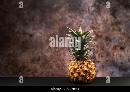 Yellow fresh pineapple on a table against the dark background. Stock Photo