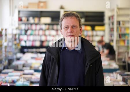 Berlin, Germany. 20th Apr, 2021. Thorsten Willenbrock, co-manager of the bookshop 'Kisch & Co', stands in his shop. The small bookstore on Oranienstraße is threatened with eviction by the Luxembourg landlord. On April 22, 2021, a lawsuit on this is to be heard in court. Credit: Jörg Carstensen/dpa/Alamy Live News Stock Photo