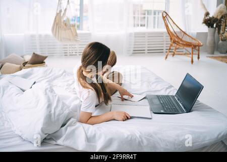 girl writes in a notebook and listens to music in bed Stock Photo