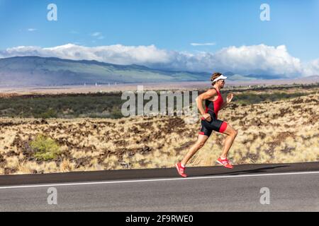 Triathlete man runner running uphill, on road at triathlon suit training for ironman. Male athlete exercising on Big Island Hawaii, USA. Fitness in Stock Photo