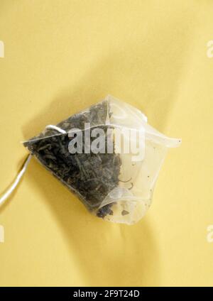 Healthy green herbal pyramid tea bag on yellow background Stock Photo