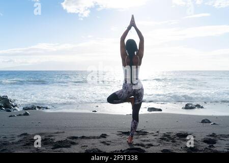 woman in sport clothes practicing yoga and meditating on beach in morning Stock Photo