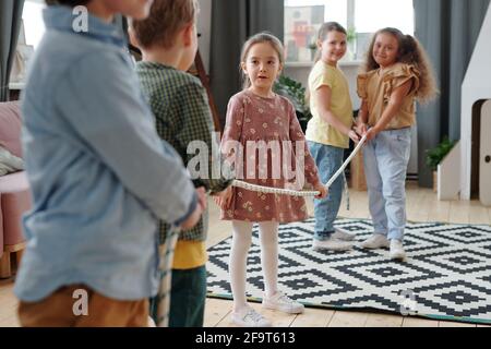 Group of children pulling the rope during game in the living room at domestic party Stock Photo