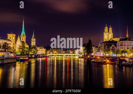 night view of illuminated skyline of the swiss city zurich dominated by towers of grossmunster cathedral and fraumunster church. Stock Photo