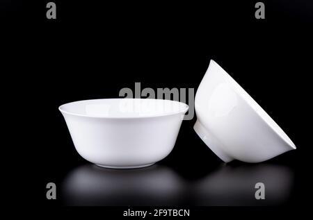 Two white porcelain bowls on a black background. Soft focus. Copy space. Stock Photo