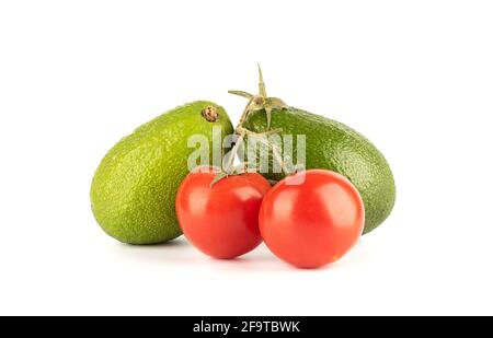 Two avocados and tomatoes on a branch isolated on a white background. Copy space. Stock Photo