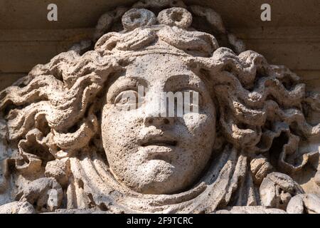Woman's face carved in stone, probably an allegory of fortune, facade ornament of an old building in Paris, France Stock Photo