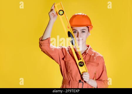 Female builder or repairer in hardhat and safety holds building level. Stock Photo