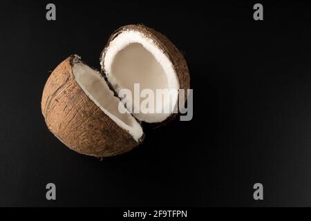 One ripe coconut divided into two parts, on a black background Stock Photo