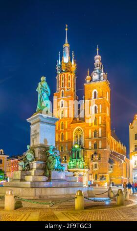 Night view of the church of Saint Mary with statue of adam mickiewicz on the rynek glowny main square in the polish city Cracow/Krakow. Stock Photo