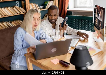 Serious multiracial business partners having online briefing meeting, discussing new strategy. Concentrated colleagues using laptop, learning Stock Photo